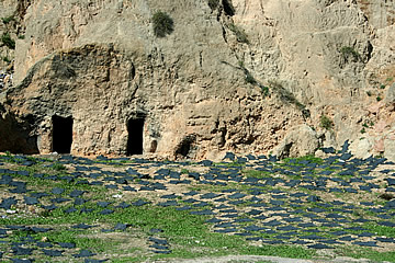 Black hides drying in the sun in front of cave dwellings